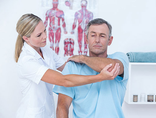 Doctor stretching a man arm in medical office