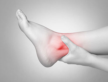 A young woman massaging her painful ankle