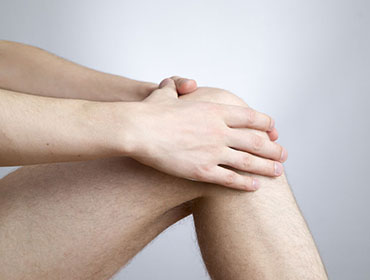 Knee pain in men on gray background